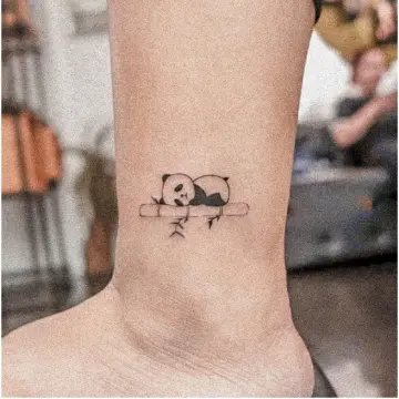 Sleepy panda tattoo on the inner forearm.