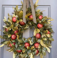 The new product is decorated with pomegranate wreath decorations in front of the door of the simulated green plant